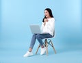 Young woman asian happy smiling in casual white cardigan with denim jeans.While her using laptop sitting on white chair isolate Royalty Free Stock Photo