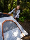 Young woman assembles a camping tent in the forest. Travel and Leisure