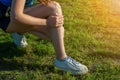 Young woman athlete outdoors sitting on grass touching painful twisted ankle. Running leg injury accident woman runners. Ankle