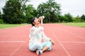 Young woman athlete sitting on runing track and drinking water in bottle.