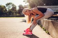 Young woman athlete touching her ankle after running on sportsground in summer. Injury during training Royalty Free Stock Photo