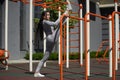 Young woman of athletic physique stretches the muscles of the legs on the horizontal bar on the sports field, while training in Royalty Free Stock Photo