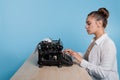 young woman author at a typewriter, writes a text. A writer at a table with a vintage typewriter