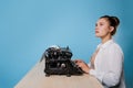 young woman author at a typewriter, writes a text. A writer at a table with a vintage typewriter