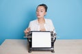 young woman author at a typewriter, writes a text. A writer at a table with a vintage typewriter