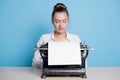 young woman author at a typewriter, writes a text. A writer at a table with a vintage typewriter