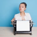 young woman author at a typewriter, writes a text. A writer at a table with a vintage typewriter