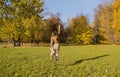 A young woman in an autumn park enjoys freedom. She jumps with arms up like superhero Wonder Woman Royalty Free Stock Photo