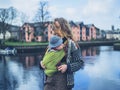 Young woman with baby in carrier sling by river Royalty Free Stock Photo