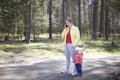 Young woman with a baby toddler talking on a mobile phone emotionally in a forest outside the city