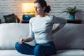 Young woman with back pain sitting on the sofa in the living room at home Royalty Free Stock Photo