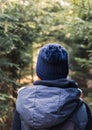 Young woman from back with redheaded in knitted hat walking in forest Royalty Free Stock Photo