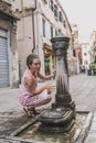 A young woman on the background of the city drinks water from a fountain Royalty Free Stock Photo