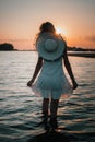 Young woman on the background of the sunset rear view. Photo of beautiful blonde in a white dress and a straw hat around Royalty Free Stock Photo