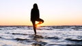 A young woman on the background of the sunset the sun on the seashore does exercises exercised by running, stretching and slumping