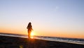 A young woman on the background of the sunset the sun on the seashore does exercises exercised by running, stretching and slumping