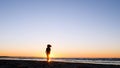 A young woman on the background of the sunset the sun on the seashore does exercises exercised by running, stretching and slumping