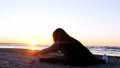 A young woman on the background of the sunset the sun on the seashore does exercises exercised by running, stretching and slumping Royalty Free Stock Photo