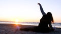 A young woman on the background of the sunset the sun on the seashore does exercises exercised by running, stretching and slumping