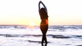 A young woman on the background of the sunset the sun on the seashore does exercises exercised by running, stretching and slumping Royalty Free Stock Photo