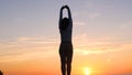 A young woman on the background of the sunset the sun on the seashore does exercises exercised by running, stretching and slumping