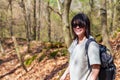 A young woman with a backpack enjoys a walk through a peaceful and lush forest on a sunny day. Royalty Free Stock Photo