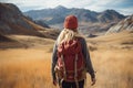 A young woman with a backpack is hiking in the mountains. A girl with a backpack travels through the mountains. A female hiker