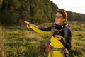 Young woman with backpack in a meadow showing way . Hiking at summertime. Geocaching Royalty Free Stock Photo