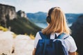 Young woman with backpack meditates listening to music with headphones and looking at view of landscape river mountain peak