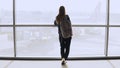 Young woman with backpack near terminal window. Caucasian female tourist using smartphone in airport lounge. Travel. 4K. Royalty Free Stock Photo