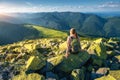 Young woman with backpack sitting on the stone