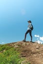Young woman with backpack standing on cliff edge and looking to landscape. Hiking and travel in mountain Royalty Free Stock Photo