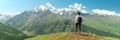 Young woman with backpack standing on cliff edge and looking to landscape. Hiking and travel in mountain Royalty Free Stock Photo