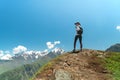 Young woman with backpack standing on cliff edge and looking to landscape Royalty Free Stock Photo