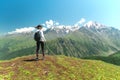 Young woman with backpack standing on cliff edge and looking to landscape Royalty Free Stock Photo