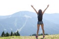 Young woman with backpack standing on cliff& x27;s edge and looking to a sky with raised hands, free space for your text. Royalty Free Stock Photo