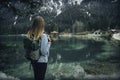 Young woman with backpack is standing on the coast of the lake Royalty Free Stock Photo