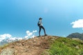 Young woman with backpack standing on top of cliff edge and looking to landscape Royalty Free Stock Photo