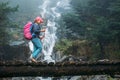 Young woman with backpack and trekking poles crossing wooden bridge near power mountain river waterfall during Makalu Barun Royalty Free Stock Photo