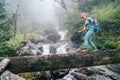 Young woman with backpack and trekking poles crossing wooden bridge near power mountain river waterfall during Makalu Barun Royalty Free Stock Photo