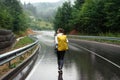 Young woman with backpack walking alone among rainy mountains