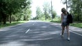 Young woman with backpack walking on the road back view