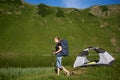 Woman tourist near camping in the mountains with backpack and trekking sticks in the morning Royalty Free Stock Photo