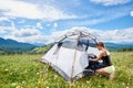 Woman tourist hiking in mountain trail, enjoying summer sunny morning in mountains near tent Royalty Free Stock Photo