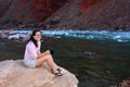 Young woman backpacker resting by Hance Rapids in the Grand Canyon.