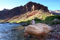 Young woman backpacker resting by Hance Rapids in the Grand Canyon.