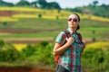 Young woman backpacker walks on the background of colored fields