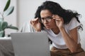 Young woman with bad eyesight using laptop, trying to work Royalty Free Stock Photo