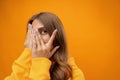 Young woman in bad mood close face by hands studio shot on yellow background Royalty Free Stock Photo