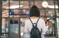 Young woman with bag and backpack in the trainstation in front of timetables